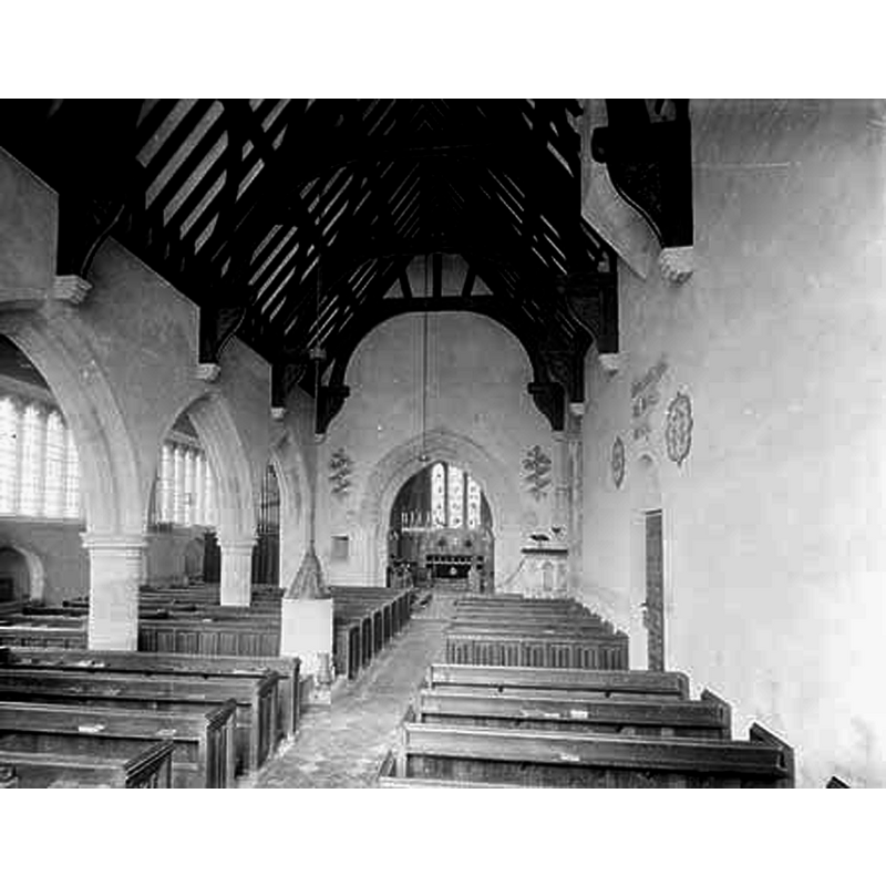 with the font and cover visible on the left, opposite the south door -- Source caption: "Looking east along the nave with the north arcade and aisle of circa 1470 visible to the left. The church has Norman origins but was altered in the medieval period and restored by Woodyer in 1864."