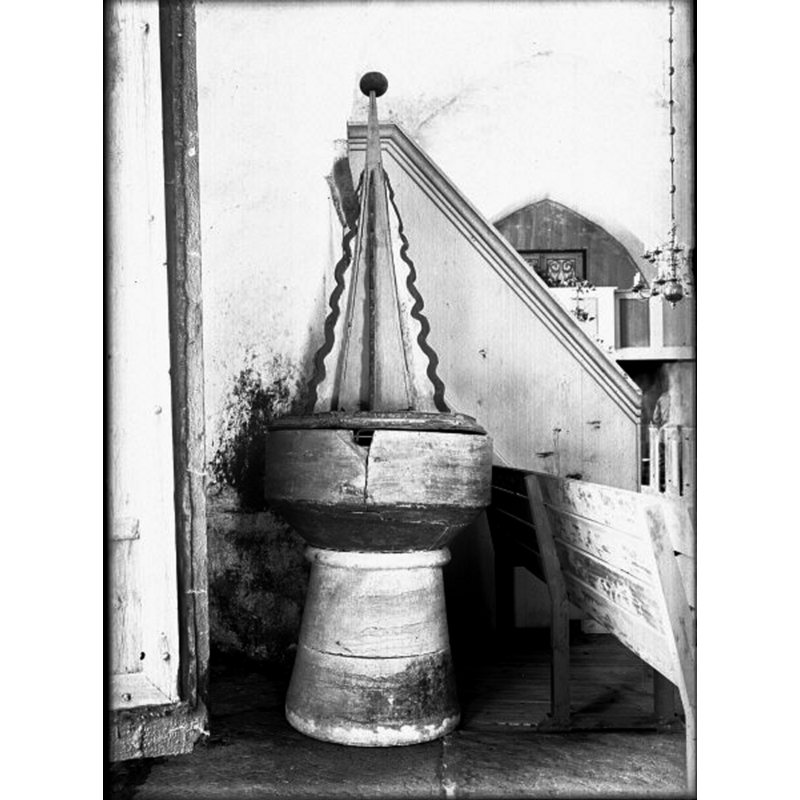 the font as shown in 1931, after its repair but before the restoration -- Source caption: "Dopfunt av kalksten. Senmedeltida. Locket från 1600-talet, "torn" på medeltida lockbotten."