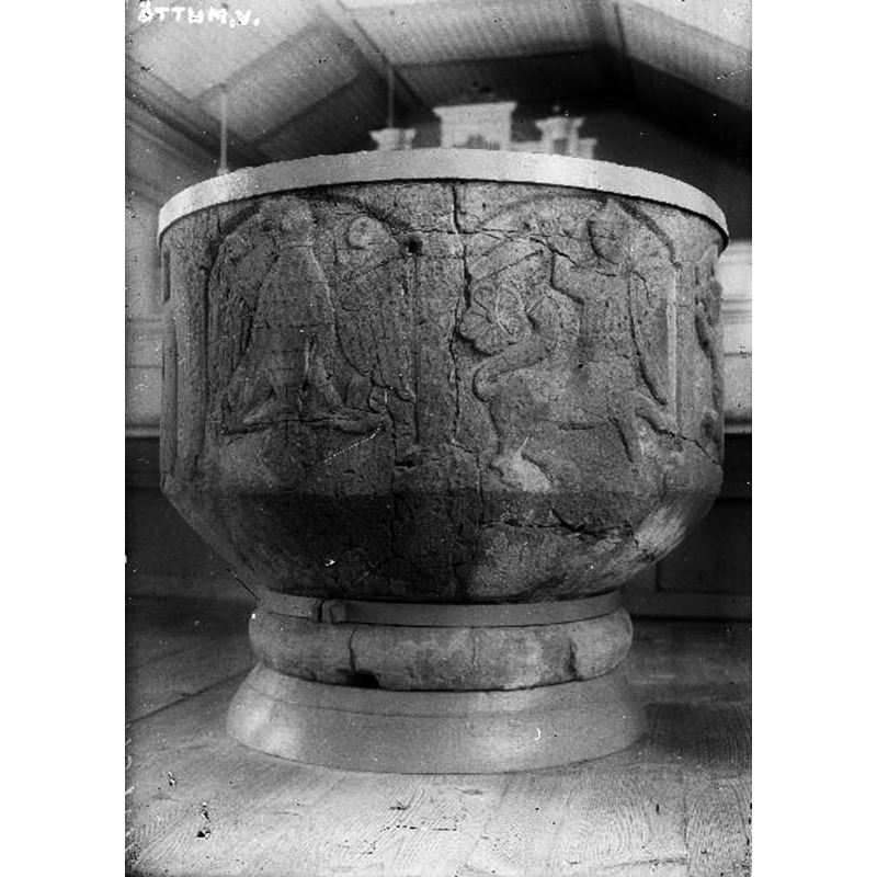 Original caption: "Dopfuntscuppa, sandsten. Indelad av arkader i fem fält. Sprucken, sammanhållen av järnband. Snabbinv. Bilder av en heraldisk örn och en stridande kantaurer [sic]."