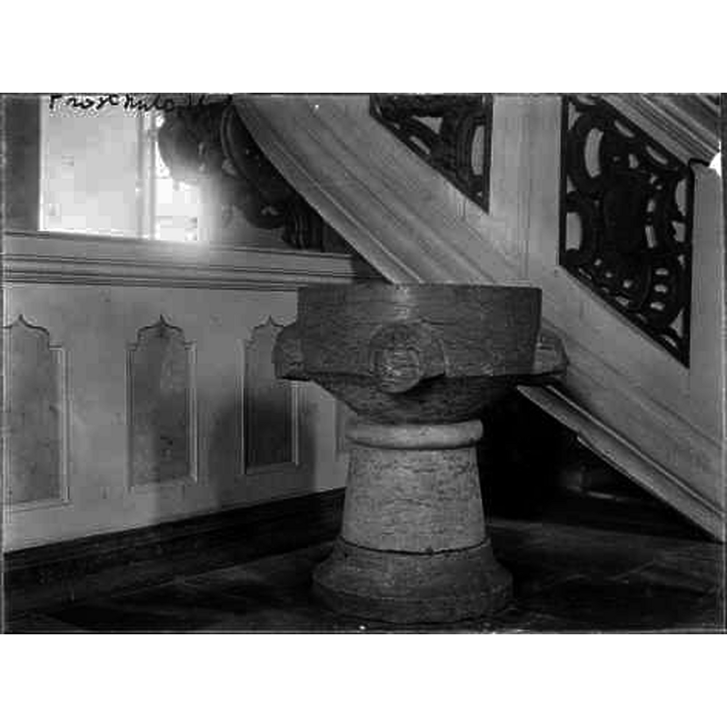 Source caption: "Dopfunt av gotländsk kalksten med uttömningshål, på cuppan fyra ansikten, 1200-talets mitt." -- the font is located at the foot of the pulpit in this image
