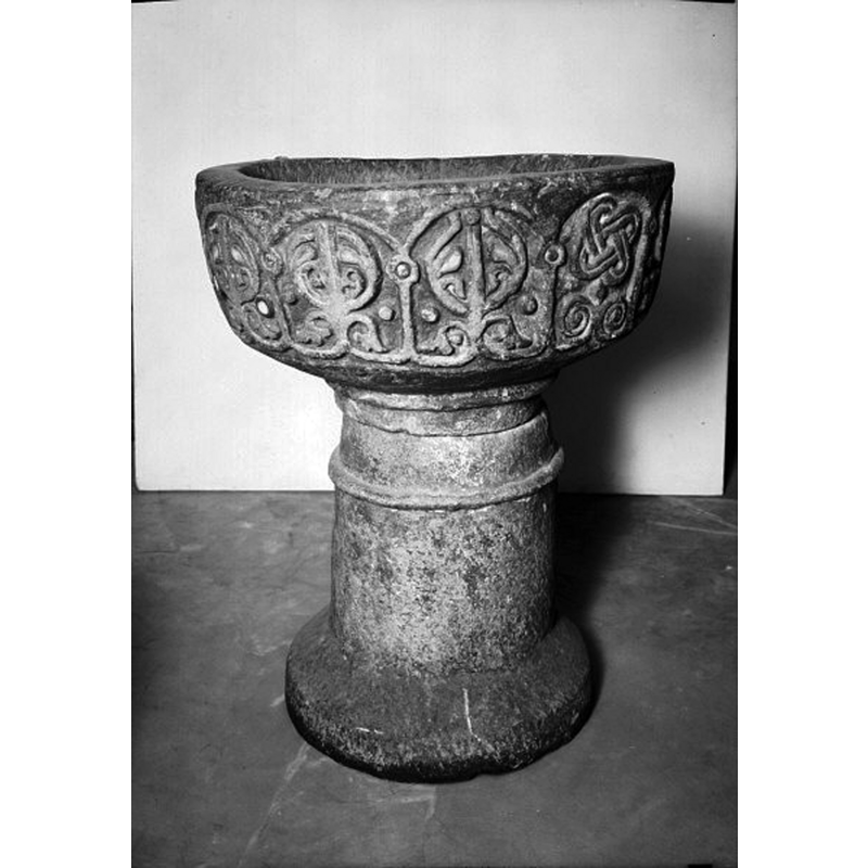 the medieval font on display at the museum -- Source caption: "Dopfunt av ljusgrå kalksten, med stiliserade uthuggna bladmönster. Omkring 1300."