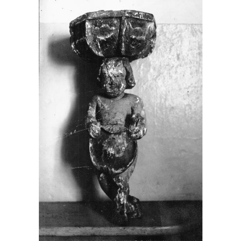 the 1693 wooden font; the wings are missing in this photograph -- Source caption: "Dopfunt, skulpterad i trä, oktogonal cuppa uppburen av putti, 1700-talet. Efter konservering."