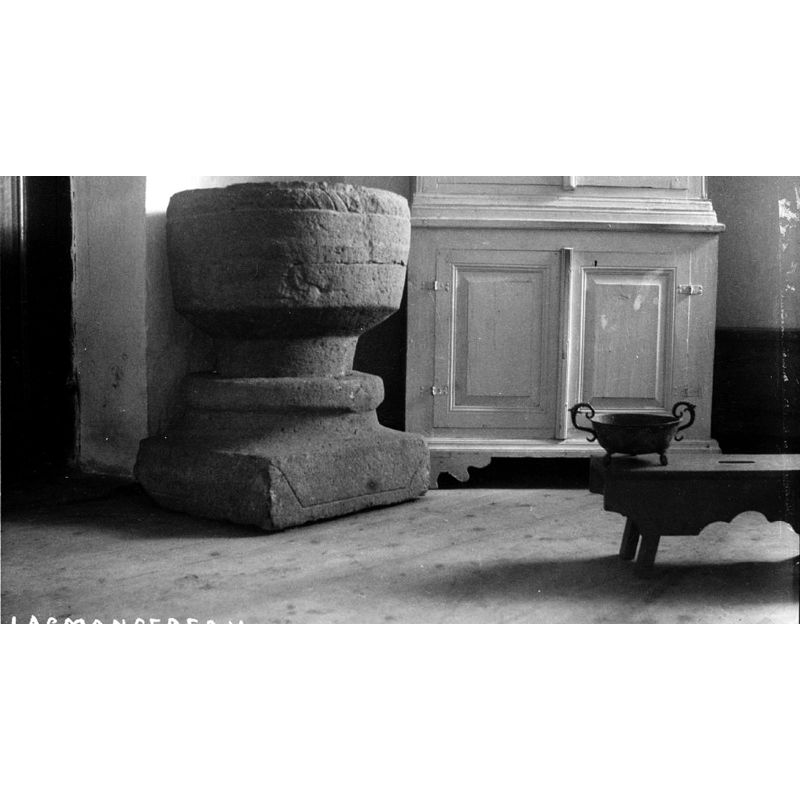 the medieval font photographed [ca. 1919?] inside the medieval church; a fire would destroy this church in 1929 but the font survived