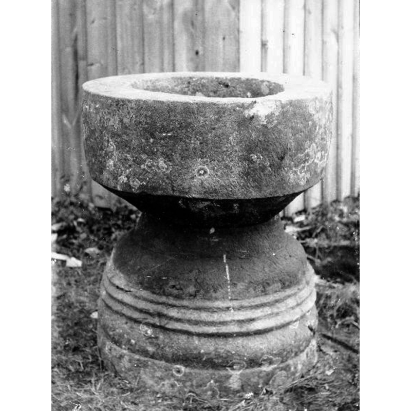this 1896 photograph shows the font also outside but from a different angle -- note that in both photographs the cylindrical half of the font is used as basin; compare this with ImageFileNos. 0200825031 (1966) and 1200825036 (2020) when the position of the two halves is reversed