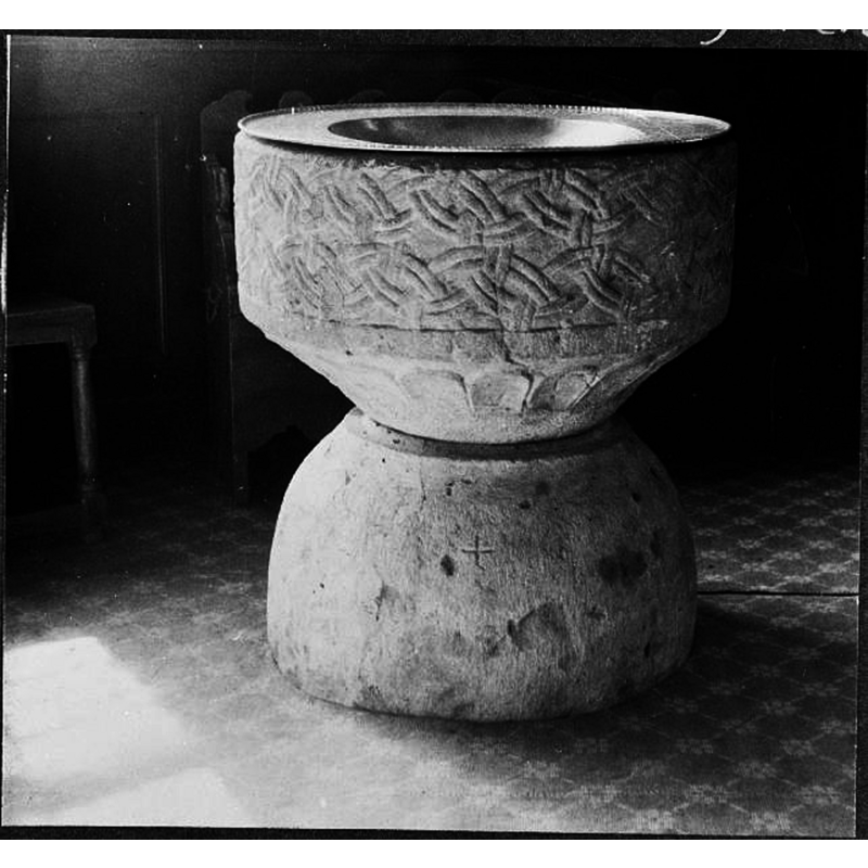 Source caption: "Toarps kyrka [...] Dopfunt, 1100- eller 1200-talet." -- according to Hallbäck (1966) the basin of a medieval font was recovered after more than a century of disuse in the churchyard and restored to the church in 1904; the base, however was discovered in a bog west of the church in 1942 and was restored to the church -- the image here shows the font after its restoration incorporating the later-found base