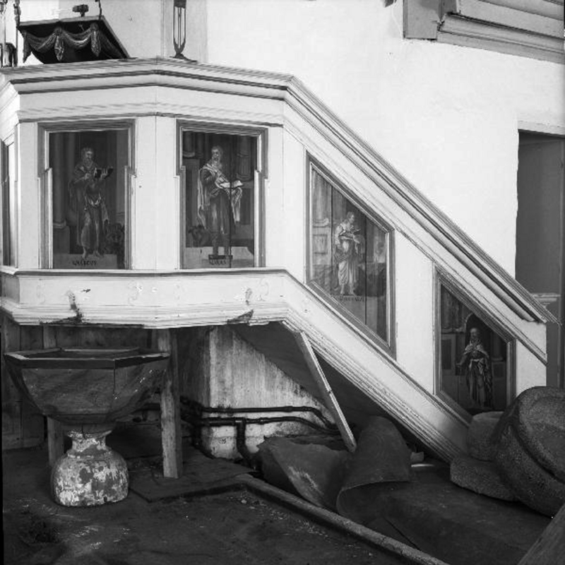 Source Caption: "Tuve kyrka [...] Predikstol, 1700-talet. Före konserveringen 1959." -- teo fonts are visible here: the medieval font , with the basin off its base, on the right, and an octagonal font of a later date(?) is right beneath the pulpit