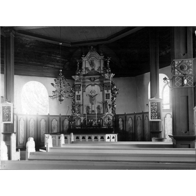 Source caption: " 	Västra Tunhems kyrka [...] Interiör mot altaret. Bänkkvarter." -- the top of the font is visible beneath the psalm board