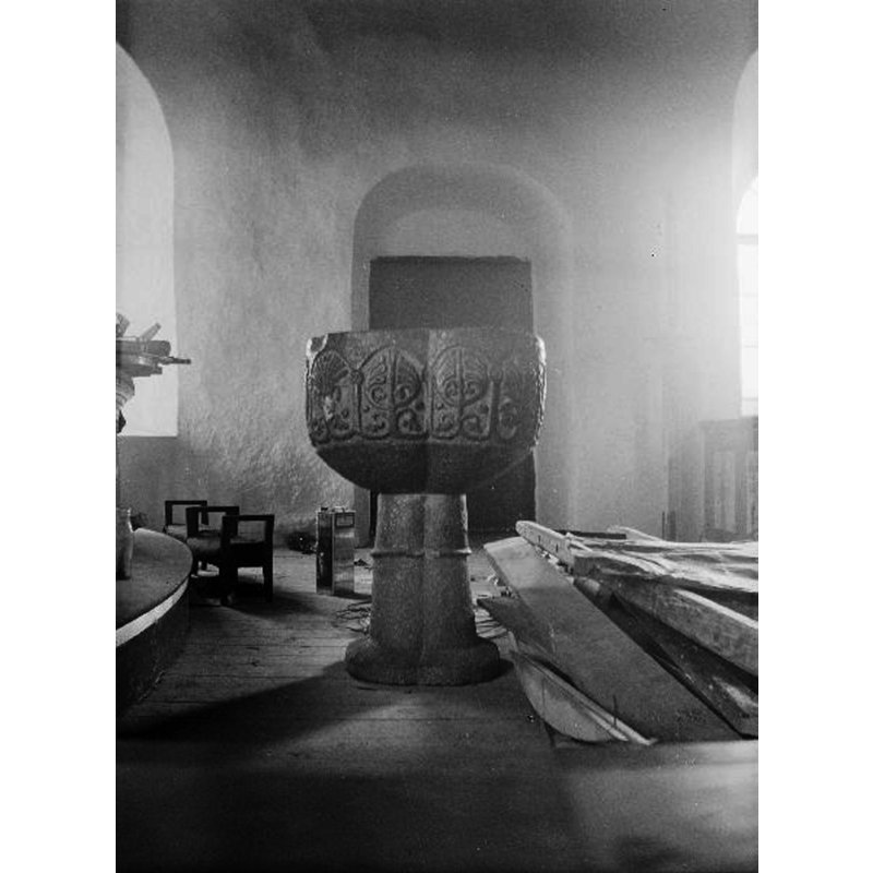 Source caption; "Älekulla kyrka [...] Dopfunt i täljsten. Kyrkans äldsta inventarium. Utan uttömningshål, fyrpassformad med enkel arkadindelning. Vegetativa ornament i relief. 1300-talet."
