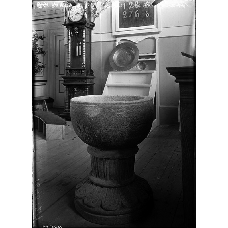 Source caption: "Stala kyrka [...] Dopfunt av täljsten. 1200-talet." -- the metal baptismal dish is visible on a shelf in the background