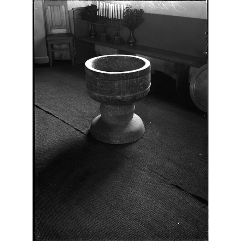 the baptismal dish is partially visible on the right side of the image, standing against a bench