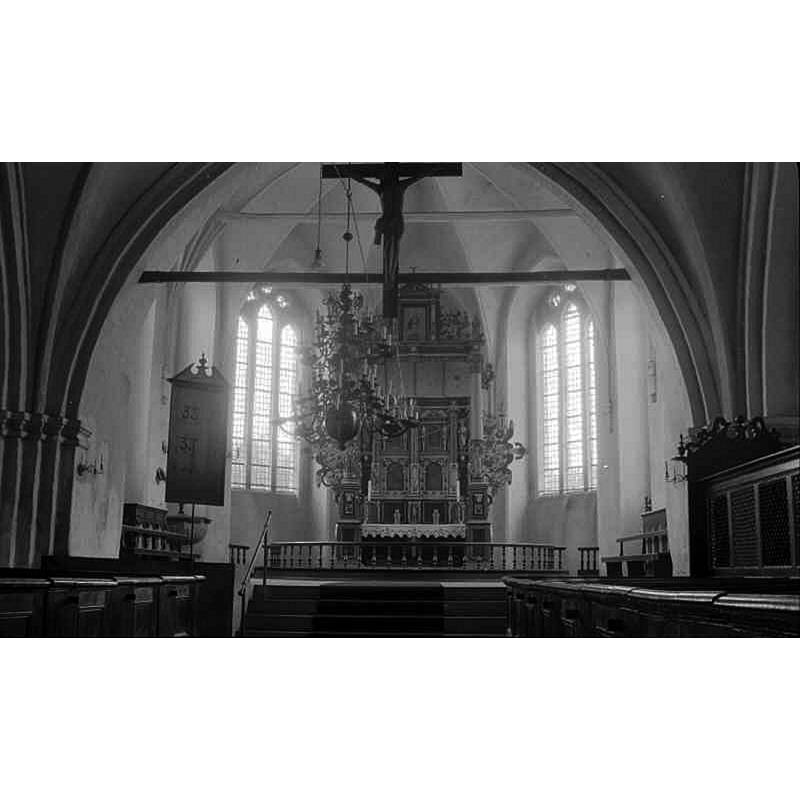Source caption: "Skanörs kyrka (Sankt Olofs kyrka) [...] Interiör mot öster." -- showing the baptismal font on the left [north] side of the chancel, behind the psalm board