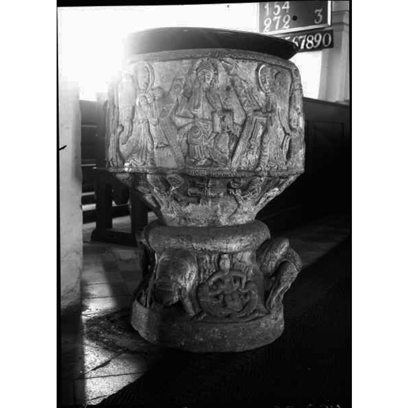 Source caption: "Östra Hoby kyrka [...] Dopfunt av sandsten, cylindrisk, av Magister Majestatis, 1100-talet." -- the object on top is probably the baptismal dish