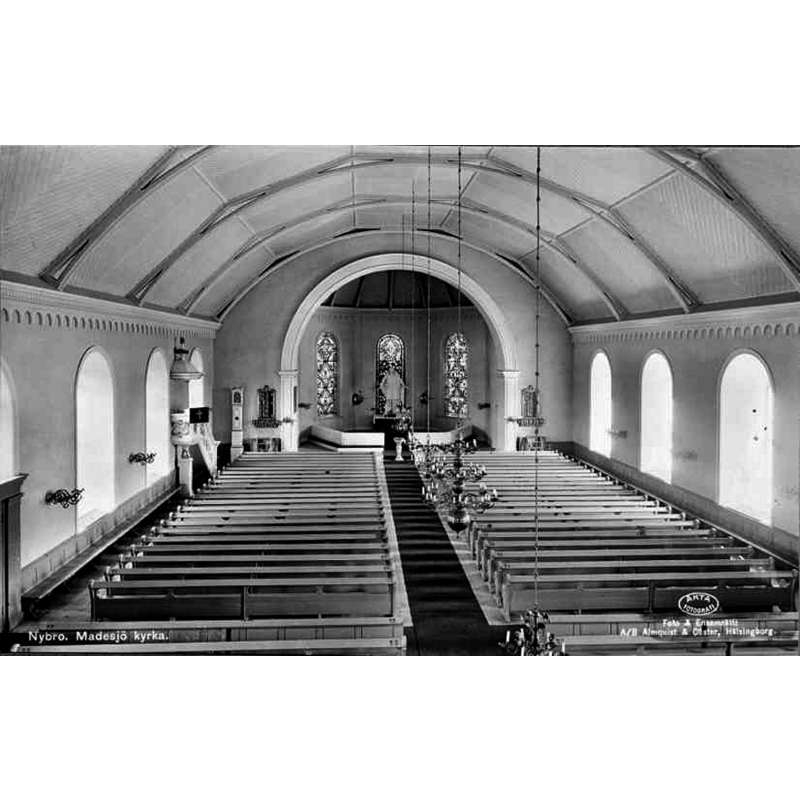 Source caption: "Madesjö [nya] kyrka [...] Interiör mot öster, vykort, omkring 1930." -- showing the 17thC baptismal font in the centre aisle, far [east] end