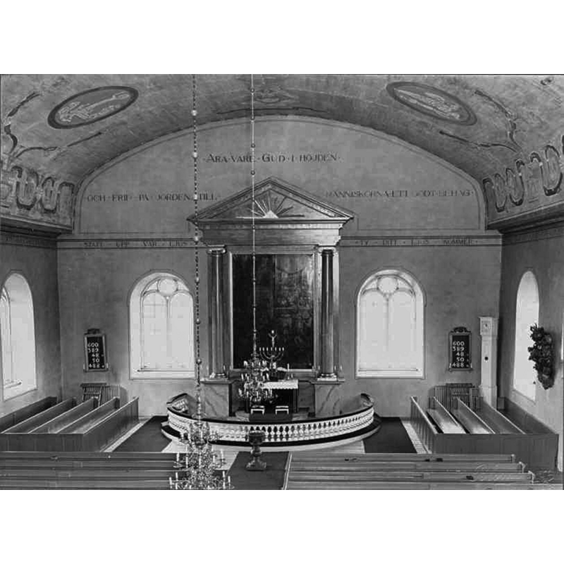 Source caption: "Ryssby kyrka [...] Interiör mot öster." [NB: the interior shown here, with the baptismal font visible in the centre of the image, just west of the communion railing, is that of the building that replaced the original medieval church in 1750; this building would be totally destroyed by fire in December 2001; a new church would be built to replace it, and was consecrated in 2005]