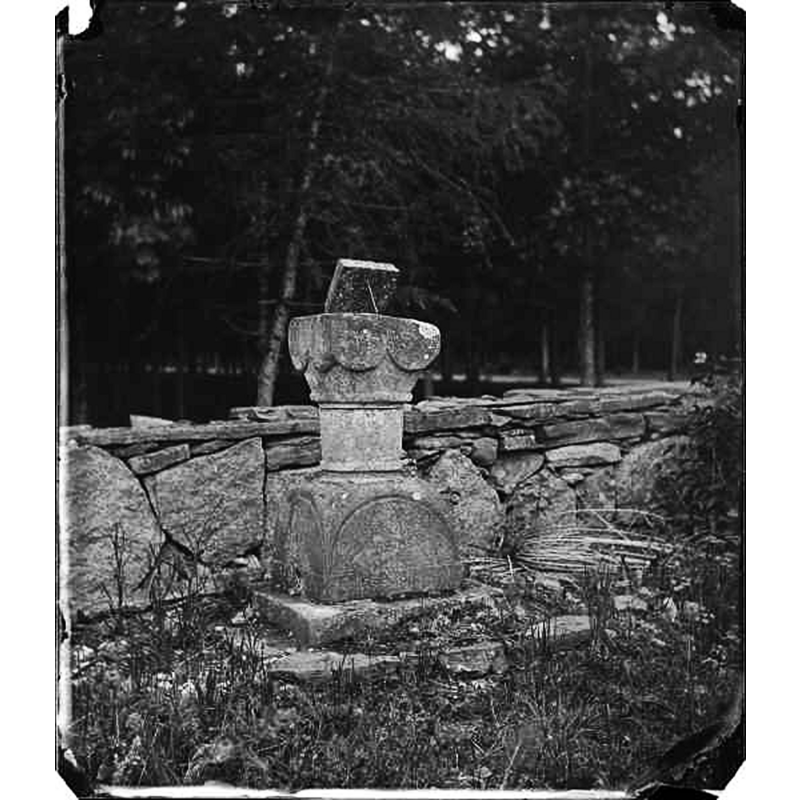 Source caption: "Visingsö, Brahekyrkan. Medeltida dopfunt, kvadratisk kuppa med avfasade hörn nedtill, stående på kyrkogården." -- NB: there is a 1906 photograph showng the font upright inside the church [cf. Image File No. 0230815004]