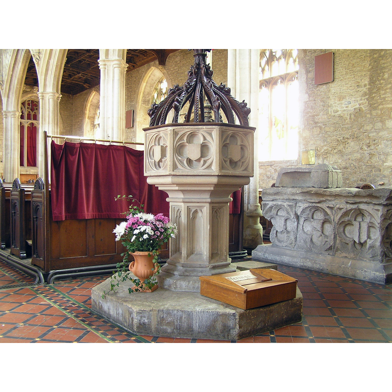 the 19th-century font in the foreground -- in the background, on the large stone artifact below the window is the fragment of the 12thC font here