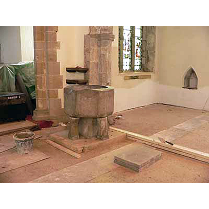 the font being installed in its new location at the east end of the nave, by the north pillar of the chancel arch, in 2007