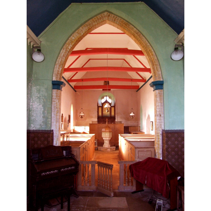 the font and cover at the west end of the nave; the font is from the earlier church