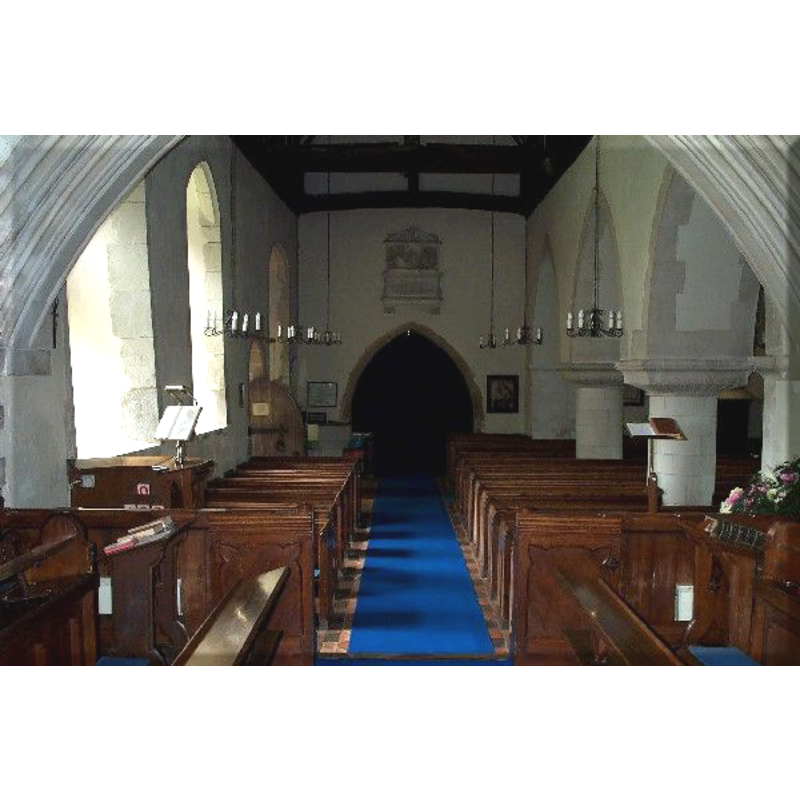 the top of the font visible at the west end, behind the bank of pews on the south (left) side