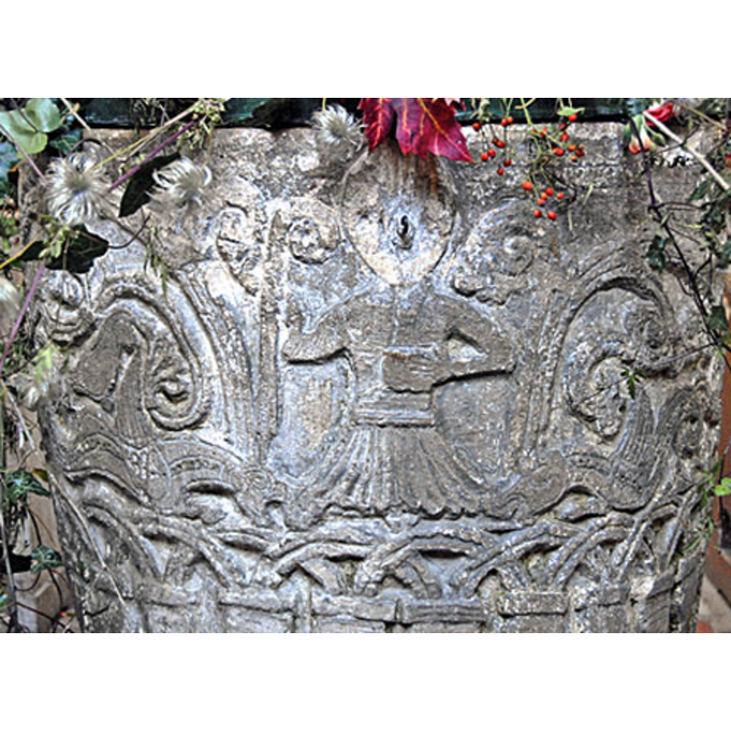 There is only one scene on the font, on the western side [on the east side in Paley (1844)], which shows a figure holding a bishop's staff (Christ or St. Michael or Bishop?) (the head is defaced) piercing the head of a serpent with the bishop's staff. A second serpent is carved on the right side of the figure. This is carved in the upper register along with an ornate acanthus motif encircling the remainder of the bowl. The lower register of the bowl has an acade, with its arches over-lapping around the bowl.