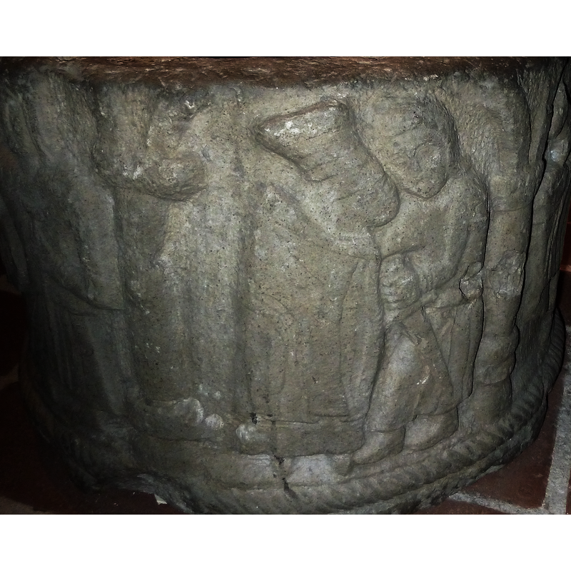 the figure on the left is probably female, and is wearing a luxurious hat and cape [cf. Font notes]