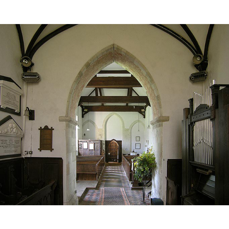 at the back (west) the entranceway; to the right of it, in the bank of pews, the top of the font and its cover can be discerned