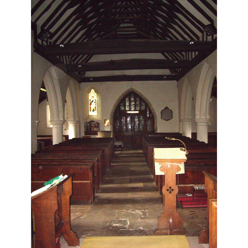 the upper part of the basin of the font is visible behind the left (south) bank of pews