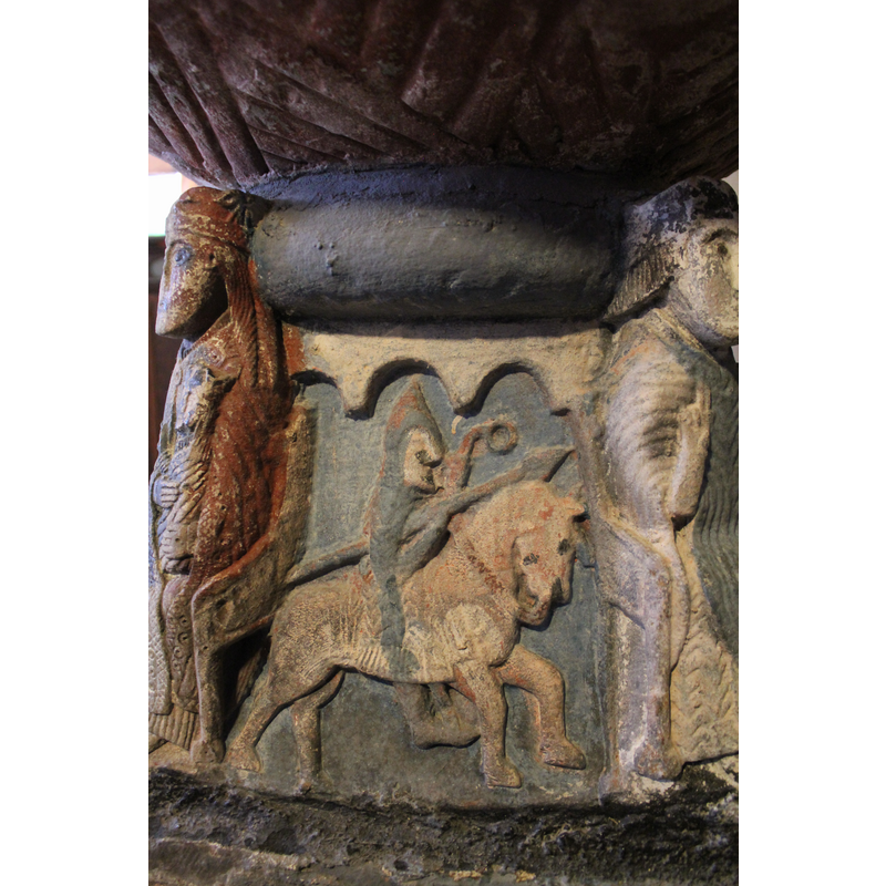 on the north side of the basin; a warrior, mounted, wears pointed helmet with nose protection and coat of armour, carries a pointed lance in his right hand and the left holds horse's bridle which has a ring at the end of it.. His feet are in stirrups.