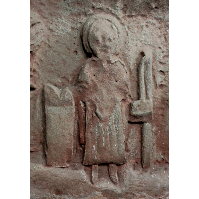 on the east side of the base -- orientation is approximate -- Haloed person, full frontal, standing figure - Moses (?): the tablets to the left - to the right, a staff and hanging bag