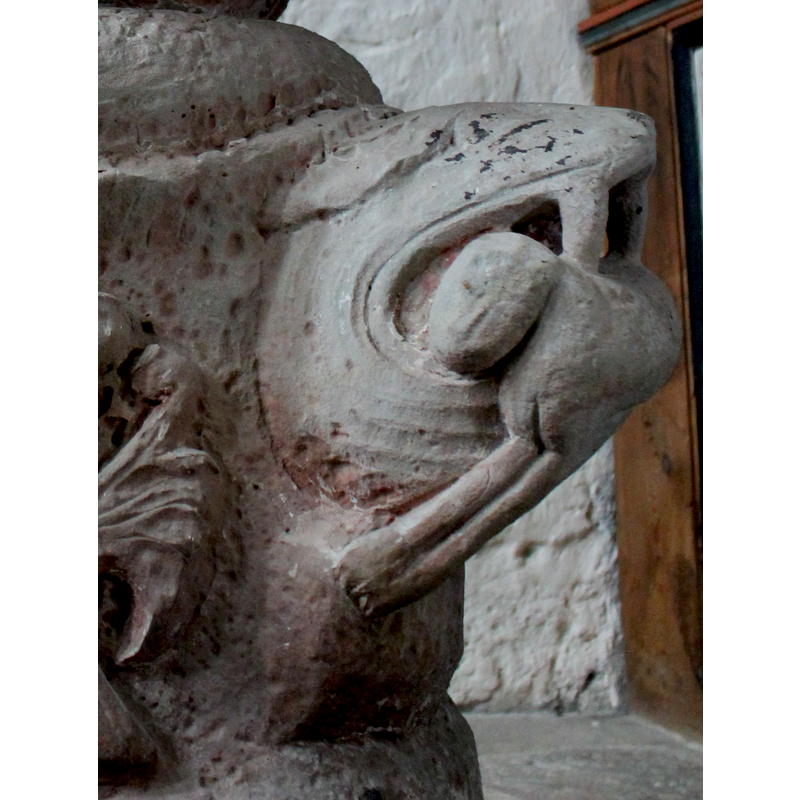 on the northwest side of the base -- orientation is approximate -- the head resembles a saurian with large fangs; the prey is a quadruped with a quasi-human face