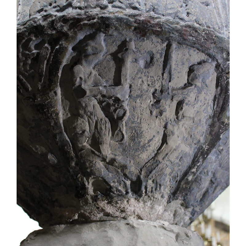 beneath one of the Passion scenes; two standing figures facing each other; the one on the left holds up a cross; the facing figure on the right wields a sword; in the bottom left corner is a seated or semi-lying figure with hands together in prayer