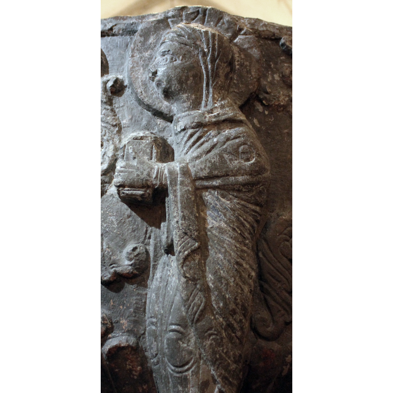 Haloed Virgin Mary stands in profile, facing left toward Gabriel. Runic inscription in the halo. Holds an ornate book and stands above the head of a snake devouring a person.