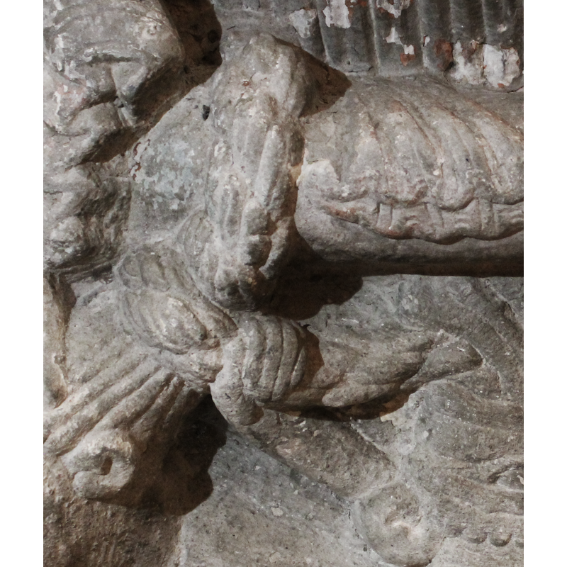 the braid is twisted around the centre ring; the hand that holds it appears to belong to the figure on the right