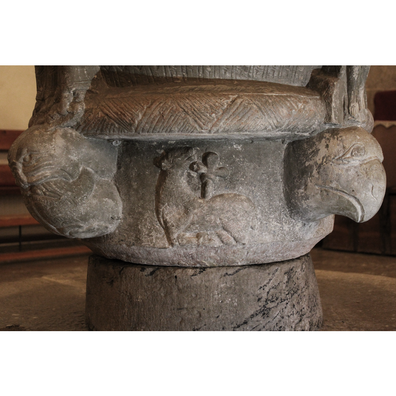 The head of the lamb looks up at Christ on the cross. The lamb holds a trefoiled cross.