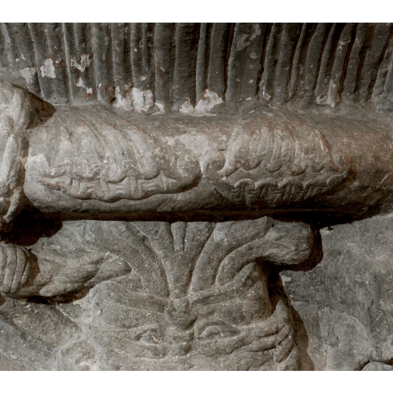 two pairs of large acanthus leaves wrapped around the ring moulding; above the large upside-down head on the base side