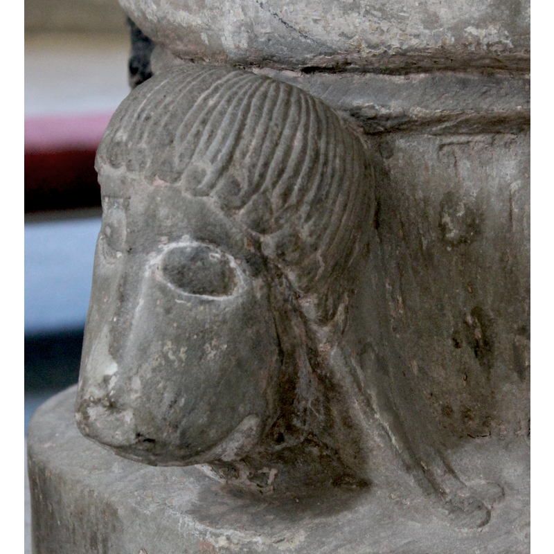 on the northwest side of the base -- right side view -- the face is animal, with long human-like tresses that could be construed as the main of a male lion