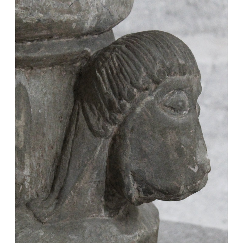 on the northwest side of the base -- left side view -- the face is animal, with long human-like tresses that could be construed as the main of a male lion