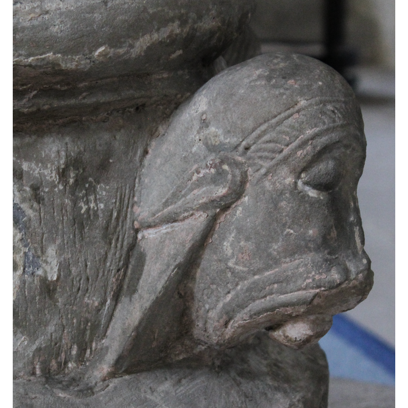 on the southwest side of the base -- left side view -- the face is animal, with long hair and pointed ears, but it wears a hair-band or diadem