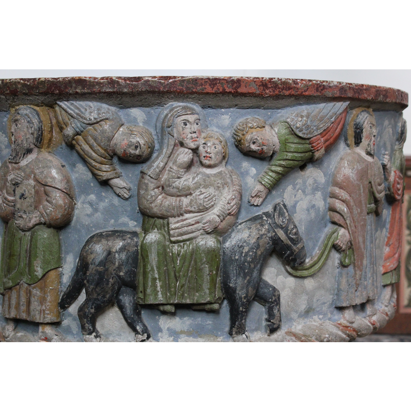 Joseph walks to the right of the horse, stands frontal, holds bridle in his right hand and gestures with his left hand. The Madonna sits frontal, side saddle on the horse with the infant in her arms. The child is blond and touches his mother's chin with his right hand. On either side of the pair are demi-angels, mirror-image, inside hands gesturing toward the pair on the horse, outer hands holding their mantle. No star present.