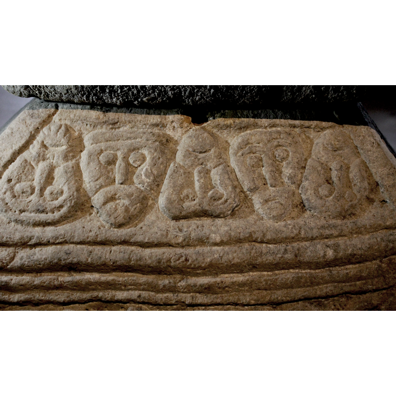 side 3, upper part of the base; the sketchy human heads are: three upside-down, two upright