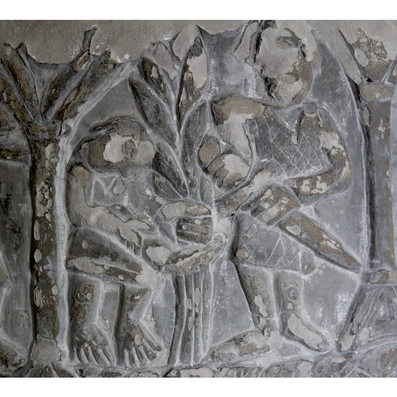 Two figures (under one arch). The figure on the left is smaller, 2/3 profile, head is bent forward, arms stretched forward holding a plant taller than he is (is this sheafs) - the right hand could be holding scythe. The person wears a short skirt and toes visible. The figure on the right is taller, full frontal, wears a coat of armour and helmet, the left arm bent at the elbow the scabber - the right arm bent at the elbow - the hand grabs the handle of the sword. He is posed in an action to remove the sword from scabber - the feet have shoes.