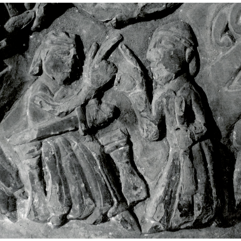 Two figures. The figure on the right stands, 2/3 view, long robes, faces left, the centre of the composition. The right arm bent at the elbow points diagonally upward and index finger extended. The left arm, flush with the body, bent at 90* angle, holds a staff across the body. The figure on the left is seated on a throne, 2/3view, looks to the other figure to the right, wears a crown, the right arm raised at shoulder height, bent at elbow, diagonally points to the hand of the other figure. The left arm holds a sword across its body and points to the left and down.