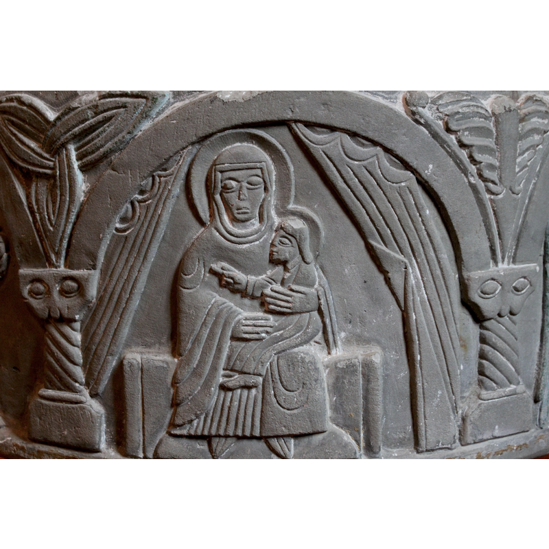 Continued from the previous arch. In this arch the haloed Madonna and Child sit on a plain bench. Drapery hangs on either side of them. Christ Child is sitting sideways pointing with right hand to the approaching Magi in the previous arch. The Madonna wears a cowl and looks outward at the viewer.