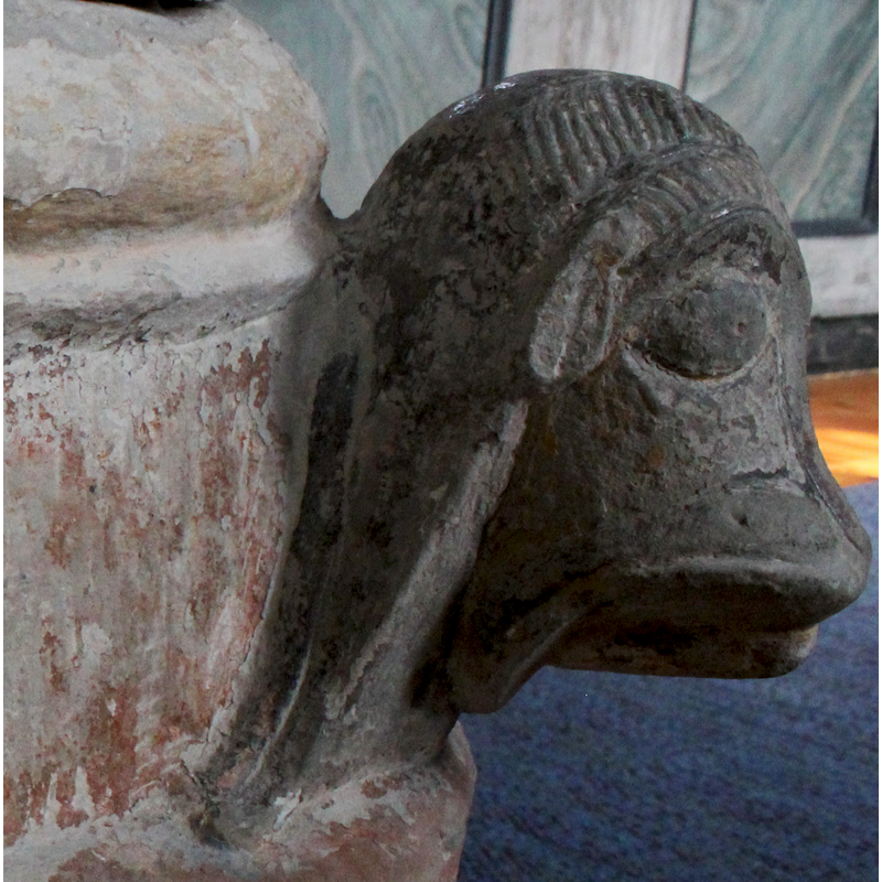 on the southeast side of the base [orientation is approximate] -- left side view; identification is tentative, as this head has a certain simian character as well