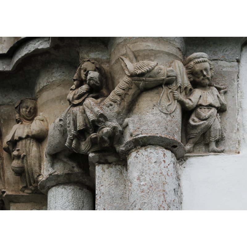 Flight to Egypt: in the centre Mary and Child on horseback; to the left a woman in attendance carries bundles over her left shoulder, and a large decorated jug with a long curved narrow spout; to the right, on the side facing south, Joseph leads the animal with his right hand and carries a covered bundle on a stick on his left shoulder