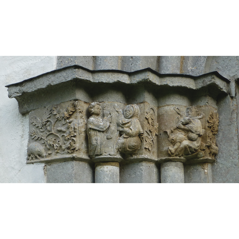this side is entirely dediocated to the Annunciation to the Shepherds [L->R]: on the narrow side facing north, a sow feeds on acorns from an oak tree; next is an angel holding up a scroll to a hooded shepherd whose right hand is raised with an open palm, the left holding a staff; after a three-leaf branch appears another shepherd, dressed in pastoral garb but his hood is off his head; he sits holding a flute of some sort, but it is a dog he holds in his left arm that blows in the instrument while the fingers of the shepherd's left hand play the holes; his right hand is raised with an open palm; at the extreme right more leaves and a scraggu sheep [a Gotland sheep?]