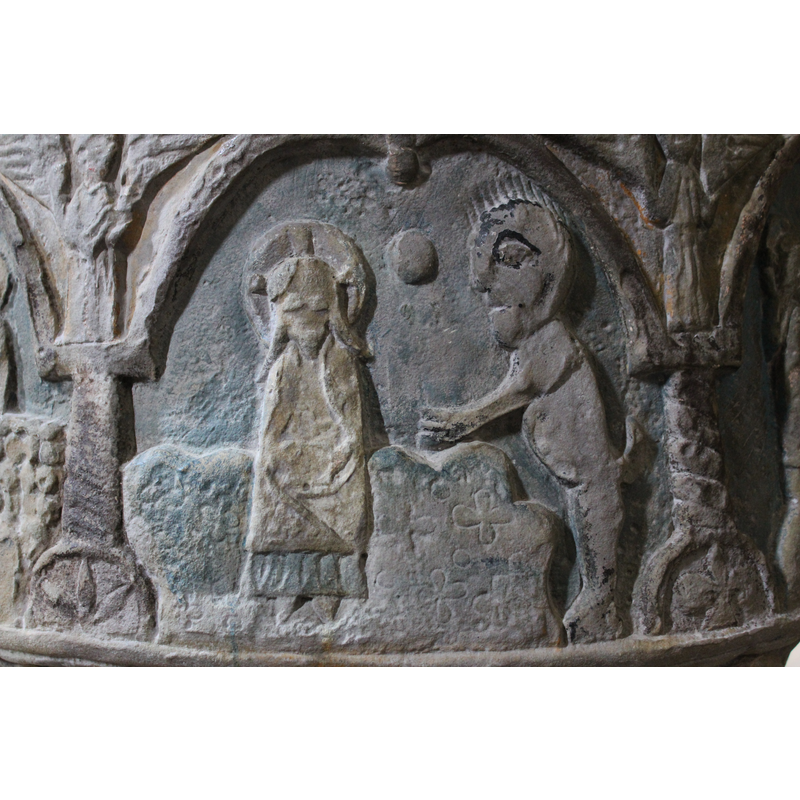 To the right of the column, two figures, the figure on the left is sitting on a large rock that is adorned with crosses and circles. The seated figures is cross-haloed  (Christ) and has long hair and a pointed beard; he is wrapped in a mantle, hands on his lap; wearing shoes. To the right of his head, again a round ball (star or sun?). To the right , in profile, a standing naked figure facing left; the head is very large and has spiked hair; the body is that of an animal (devil), front legs have three fingers pointing to Christ; it has a tail; the hind legs end in hooves. In the spandrel, an angel in the same position as the one before.