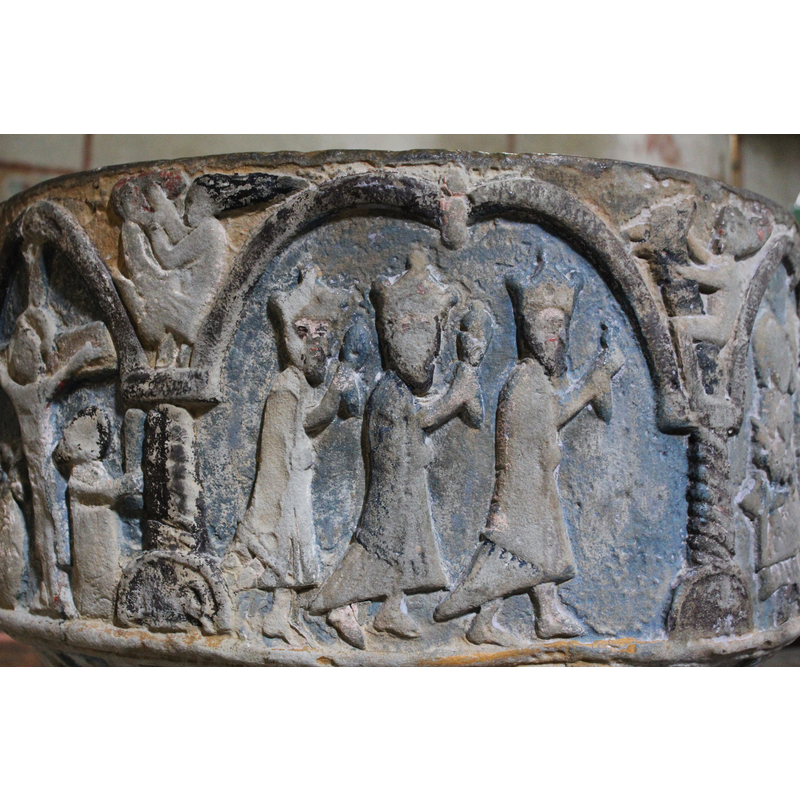 Scene spread over two arches. In the left arch the three Magi walk in profile, faces in profile, heads crowned, wearing long garments and mantles, their right arms are raised and carry gifts, the left arm holds the mantle. In the spandrel to the right, there is a long necked animal (lion) is being ridden and held by a naked figure with long hair (Samson?). In the next arch, are the Madonna and Child, enthroned, her feet resting on a rainbow, her arms hold the child on her lap. She faces full frontal. The child faces 2/3 frontal, right hand raised in benediction pose, left arm held to his chest, a rolled scroll. He is not inside her mantle. To the right of Mary's head is a round object (a star?)
