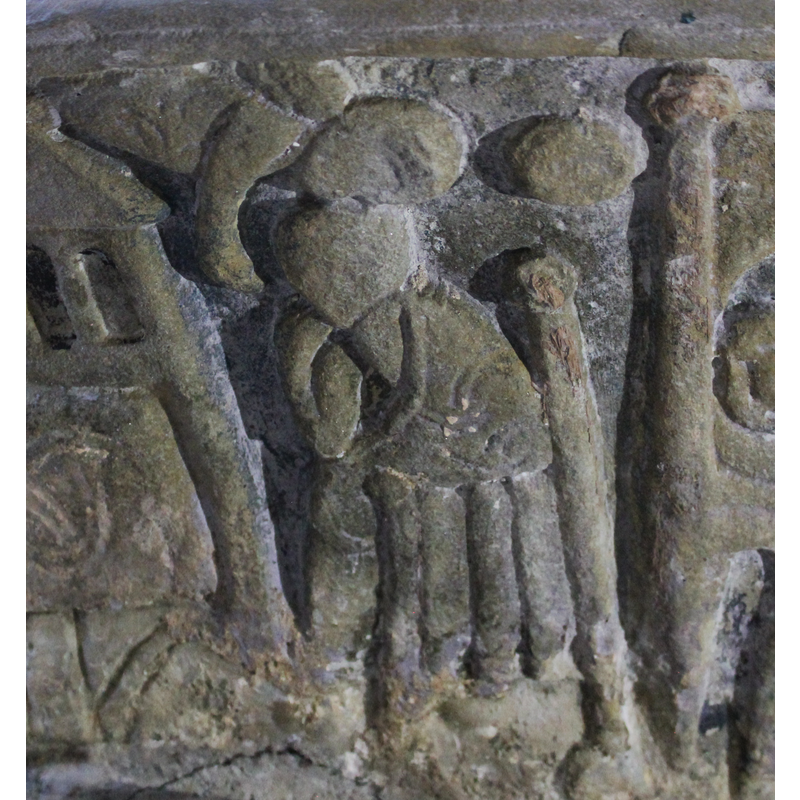Joseph sits to the right of the Nativity scene on a wooden knobbed chair. Directly above him is an angel pointing at Joseph. Joseph sits with his chin resting on his right hand.