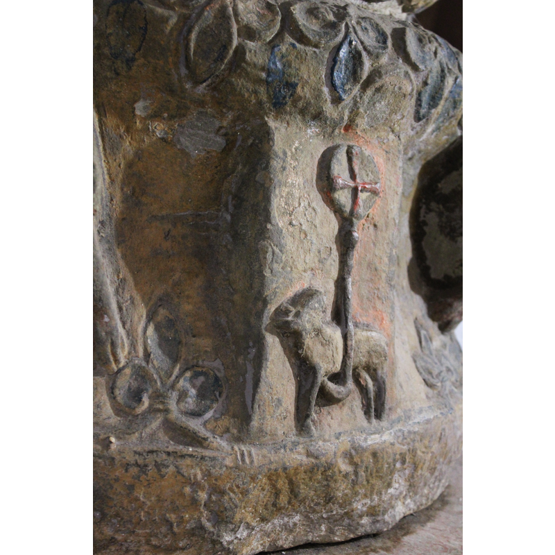 on the northwest side of the base [orientation is approximate] -- a rather indistinct quadruped passant towards the left, the head turned back and upwards, as if looking at the cross in the halo at the end of the staff; the front leg bent in the awkward angle that permits it to hold the staff. Above the lamb of God, on the underbowl is the Massacre of the Innocent; one the basin side, tight above, Christ washes the feet of an apostle. The cross is painted red.